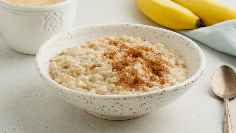 Oatmeal sits in a white bowl with a sprinkle of cinnamon on top