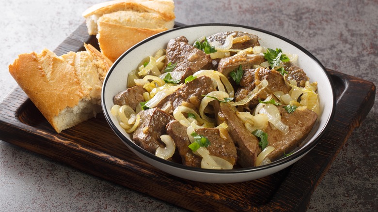 Liver and onions with bread served on a wood tray
