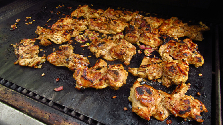 Chicken thighs are grilled on a flat top