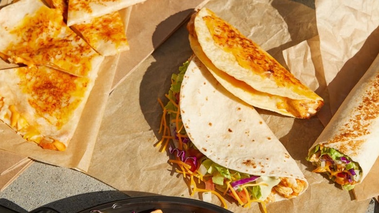 Various grilled Taco Bell items are spread out on food wrappers