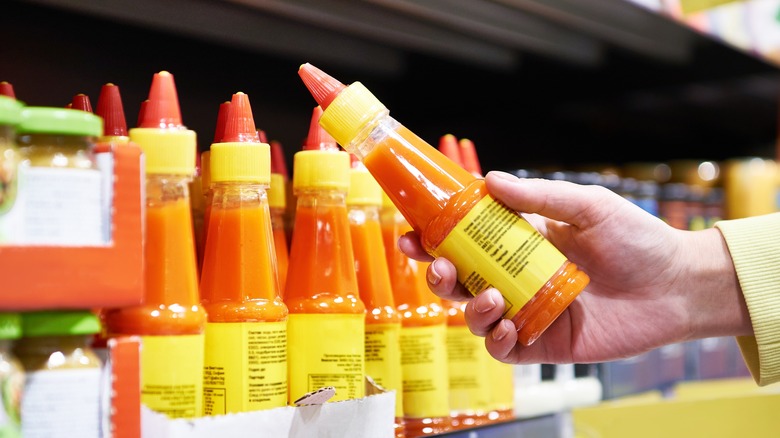 hand holding hot sauce bottle in grocery store