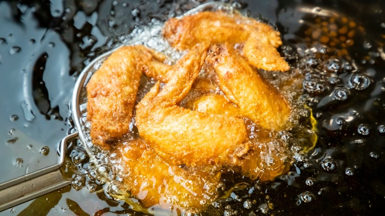Lifting a batch of chicken wings from a deep fryer