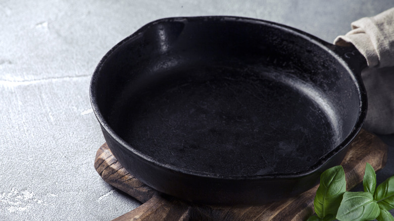 A skillet on a board with some basil