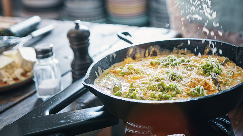 A hand grating cheese over a frittata
