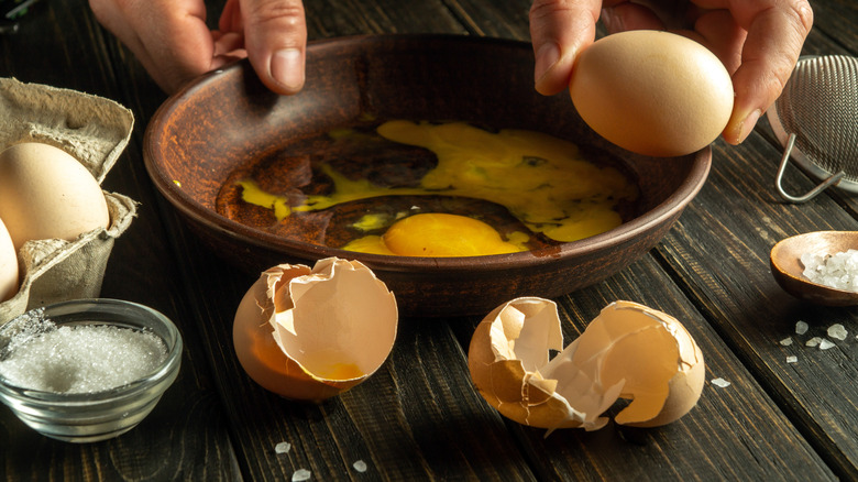 Hands cracking eggs into a bowl
