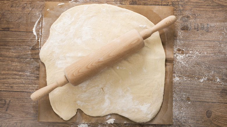 Uncooked pastry with a rolling pin