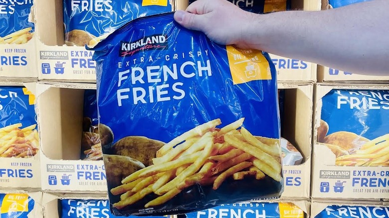 Hand holding up bag of frozen Kirkland Signature Extra-Crispy French Fries