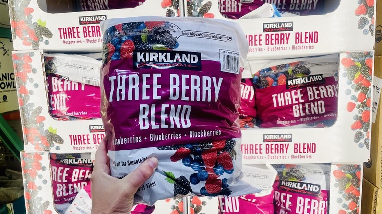 Hand holding bag of frozen Kirkland Signature Three Berry Blend
