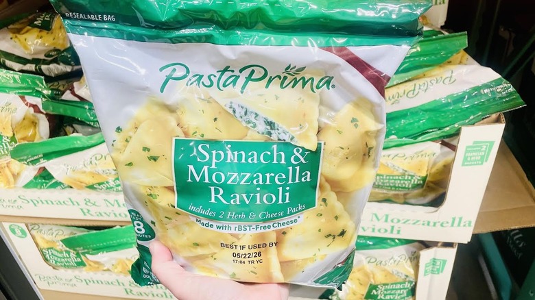 Hand holding bag of frozen Pasta Prima Spinach & Mozzarella Ravioli