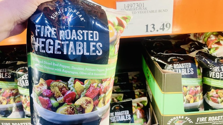 Hand holding bag of frozen Summers Peak Fire Roasted Vegetables with Costco price tag in background