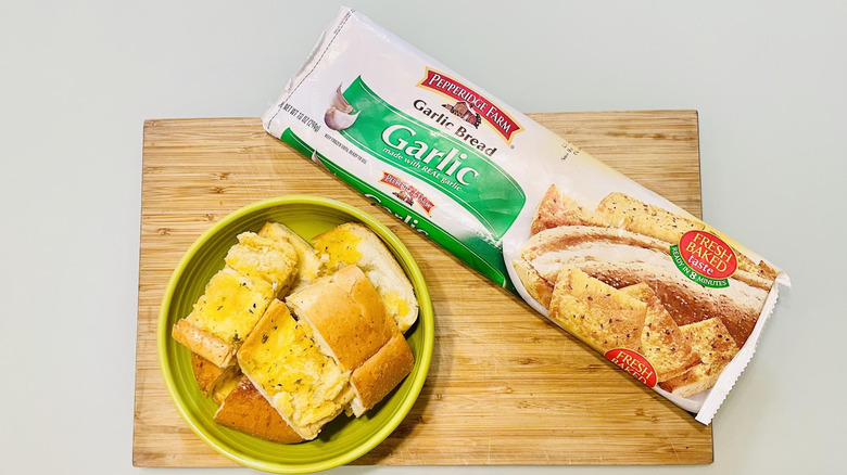 Cooked and sliced loaf of Pepperidge Farm Garlic Bread in bowl with opened packaging alongside