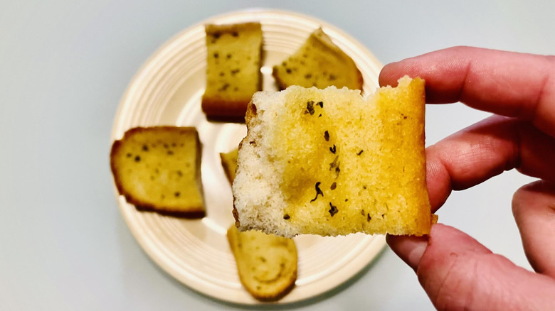 Hand holding up half eaten slice of garlic bread