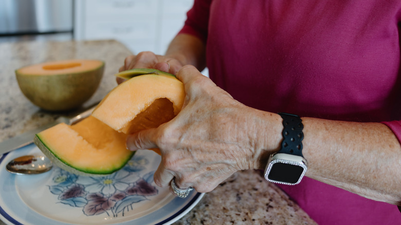Close-up of person cutting rind from cantaloupe