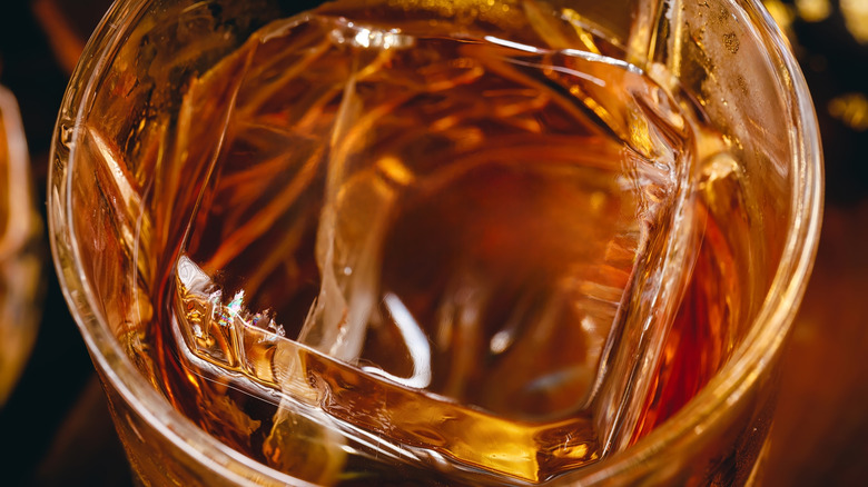 Close up of bourbon on the rocks in a glass on a table.
