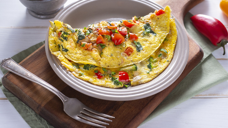 Omelet filled with vegetables on a plate with a fork