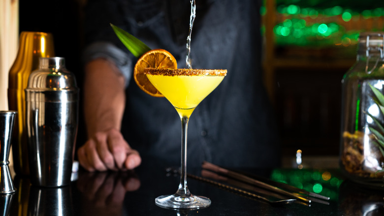 bartender pouring liquor into cocktail