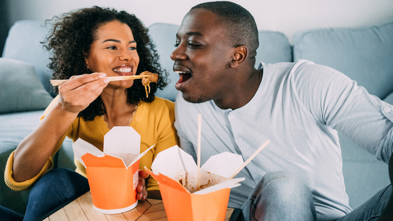 a young couple eating Chinese takeout