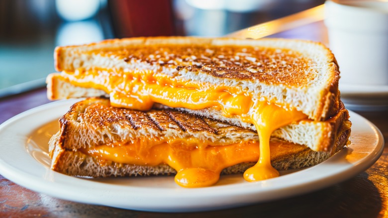 An extra crispy grilled cheese with golden cheese oozing out of the edges on a white plate