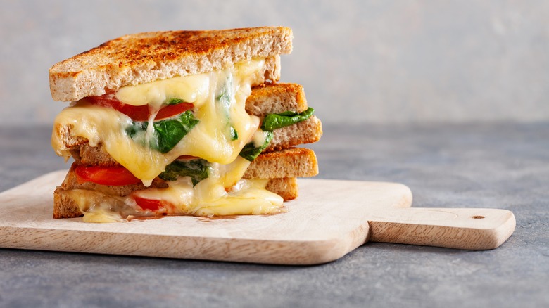 Golden brown grilled Caprese sandwiches with melty cheese stacked on a cutting board
