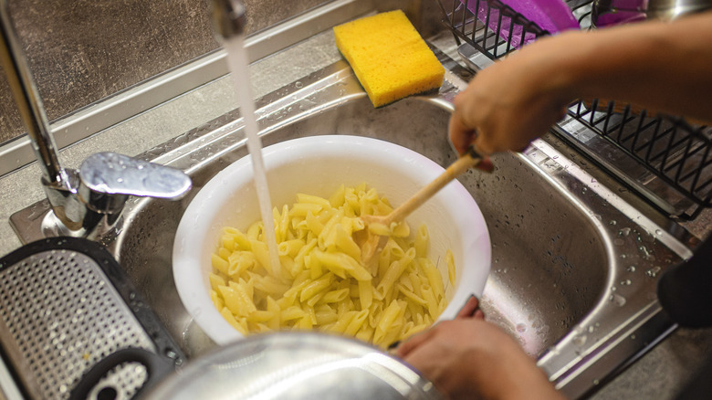 rinsing pasta with water in the sink
