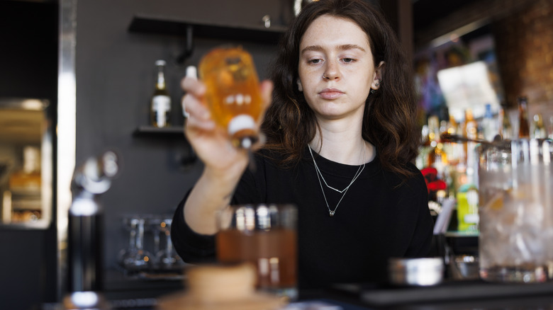 female bartender adding bitters to a cocktail 