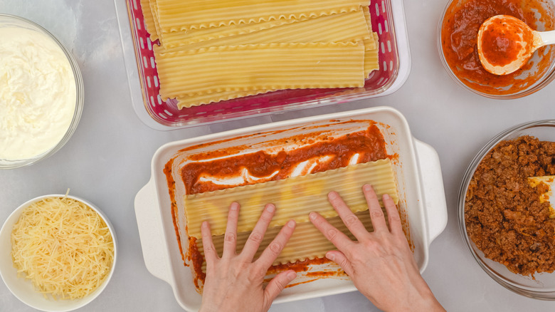Layering precooked lasagna noodles into baking dish