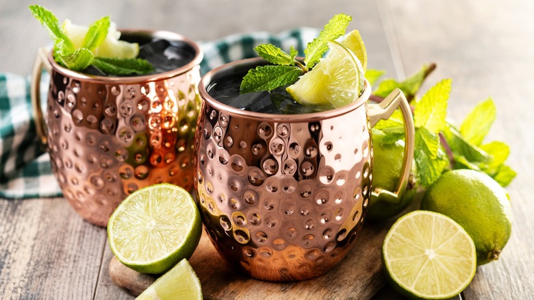 Two Moscow mules in copper mugs garnished with lime and mint
