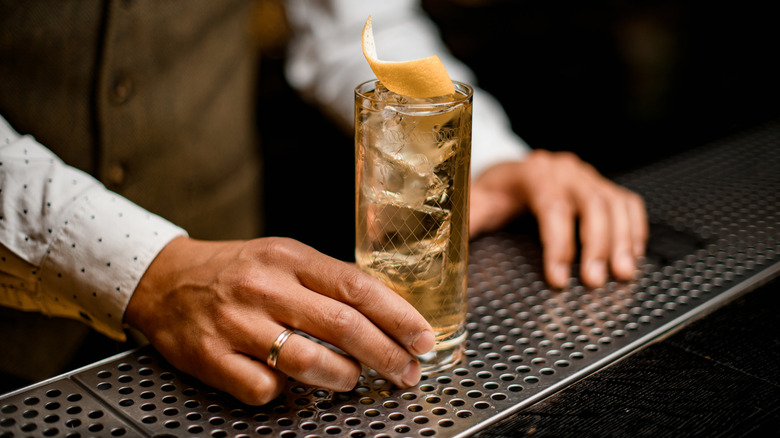 Bartender serves up a whiskey highball with twist