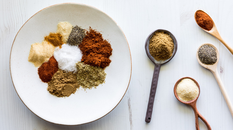 A plate of different spices that go into taco seasoning.