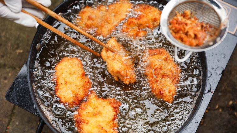 Using chopsticks to fry chicken in oil