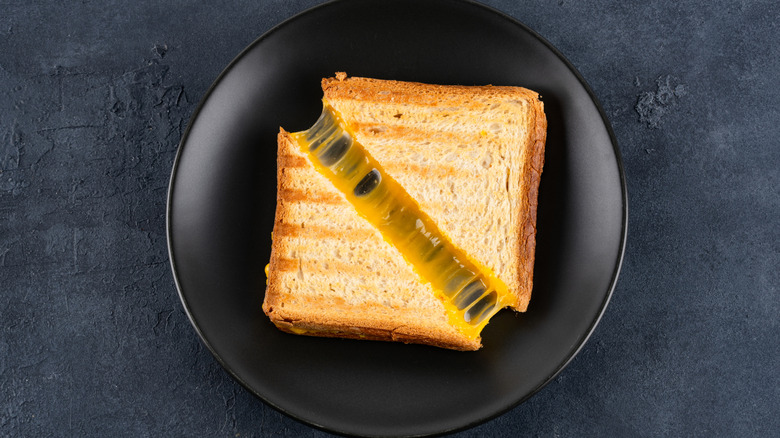 A grilled cheese sandwich on a black plate