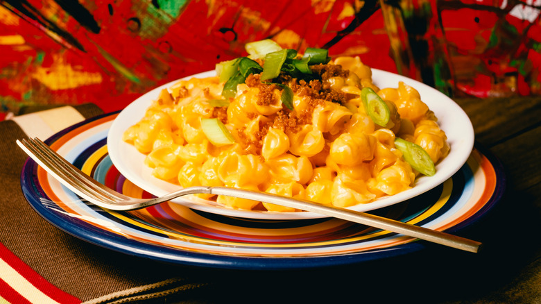 A plate of mac and cheese with breadcrumbs and green onions