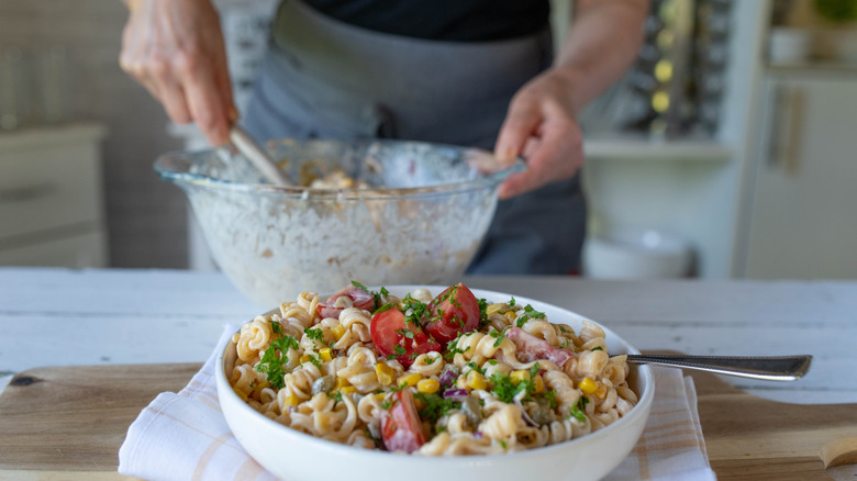 Person preparing pasta salad.