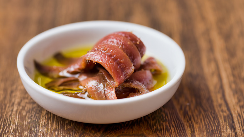 Anchovy filets in a bowl with olive oil.