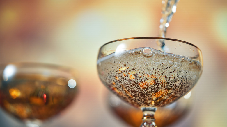 Champagne elegantly pours into a Champagne coupe glass.