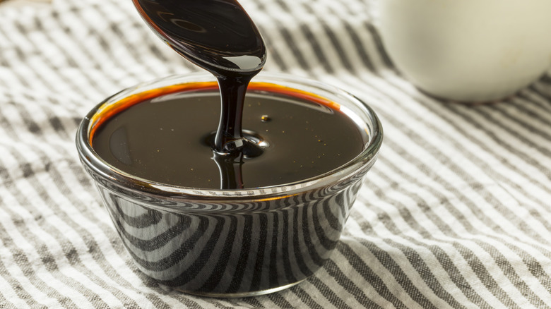 A spoon scooping molasses from a glass bowl