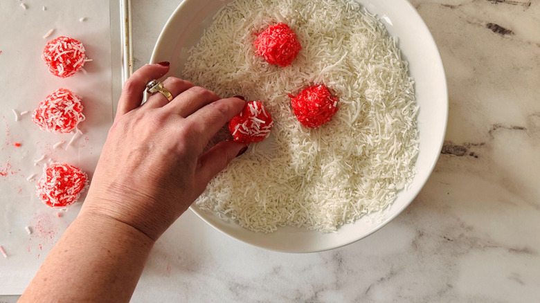 Jell-O balls in shredded coconut with hand rolling one