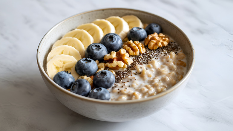 A bowl of oatmeal with blueberries, banana, walnuts, and chia seeds.