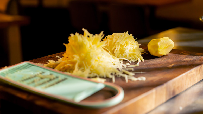 in a restaurant on an iron table on a wooden board grated young potatoes lie in a heap next to a green grate