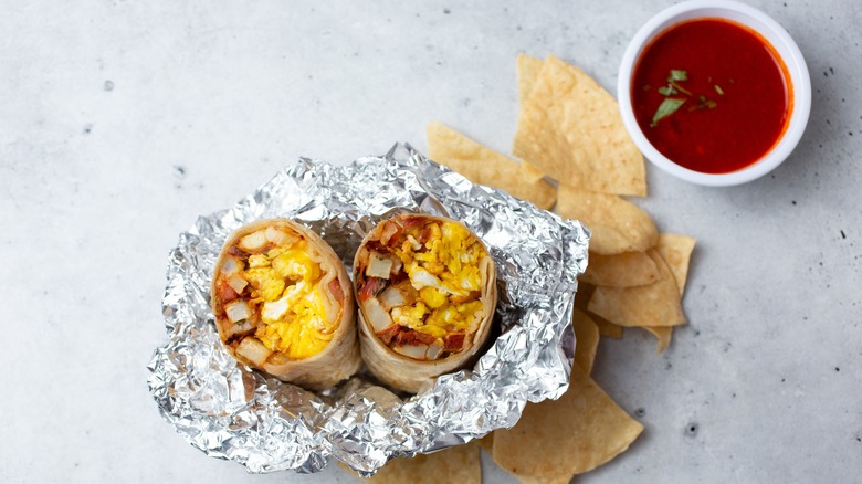 Cut burrito in foil wrapper with chips and hot sauce