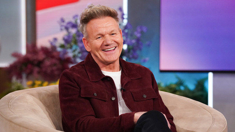 Chef Gordon Ramsay smiling as he reclines in a plush chair.