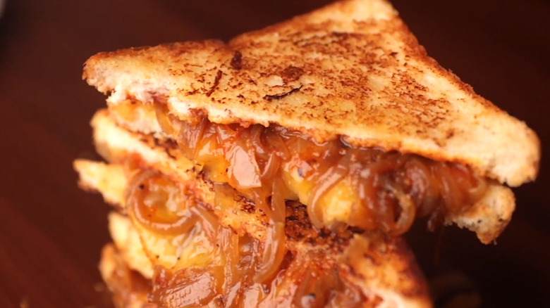 A stack of melty grilled cheese with caramelized onions