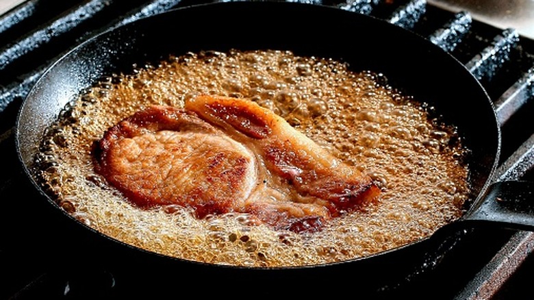 Pork chop on the stove cooking in oil.