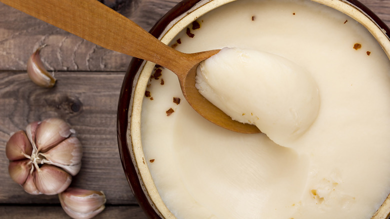 bacon grease solidified in jar with wooden spoon 