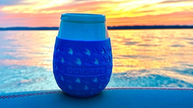 A blue Goverre sipping glass next to a lake