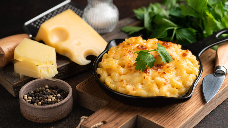 Baked mac and cheese in a cast iron skillet with cheese, salt and pepper, and parsley.