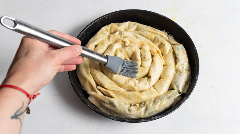 brushing butter on spiral spanakopita
