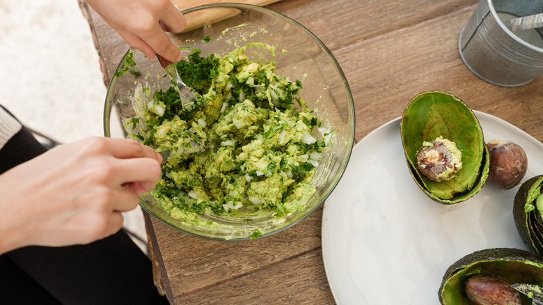 Person mixing guacamole in a bowl