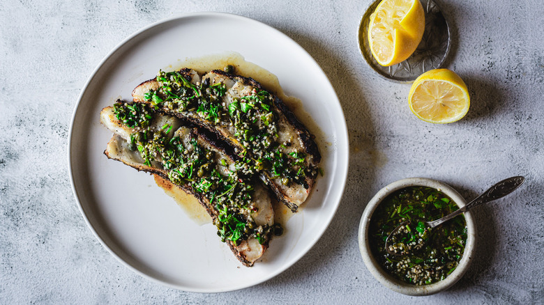 Chilean sea bass on a plate with sauce and lemon halves