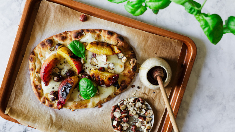 Flatbread on baking sheet with basil and toppings